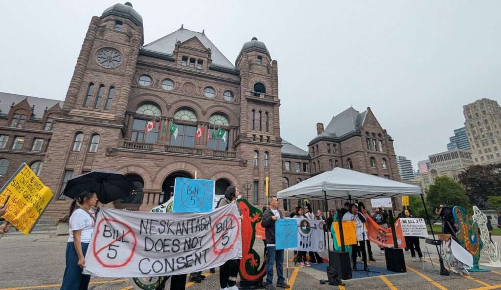 Members of Neskantaga First Nation speak at a rally opposing Bill 5 at Queen's Park on May 28, 2025. Their sign reads "Neskantaga Does Not Consent."